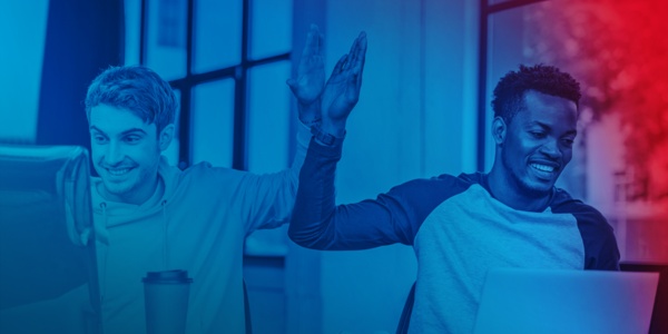 Zwei Personen sitzen am PC und geben sich einen High-Five.