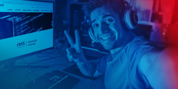 Person mit Headset sitzt am PC und macht ein Victory-Zeichen in die Kamera. Auf dem Monitor ist die ctrlX AUTOMATION Microsite zu sehen.