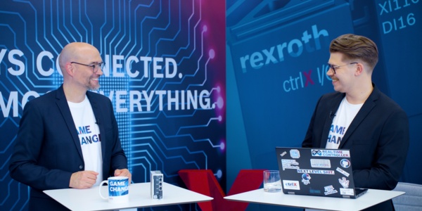Gastgeber Christian Zentraf und sein Gast Benedikt Rüb stehen an Besprechungstischen und sprechen über den ctrlX Configurator, dem Konfigurationstool der Automatisierungslösung ctrlX AUTOMATION