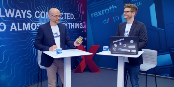 Gastgeber Christian Zentraf und sein Gast Christoph Büttner stehen an Besprechungstischen und sprechen über ctrlX SAFETY, die Sicherheitskleinsteuerung der Automatisierungslösung ctrlX AUTOMATION
