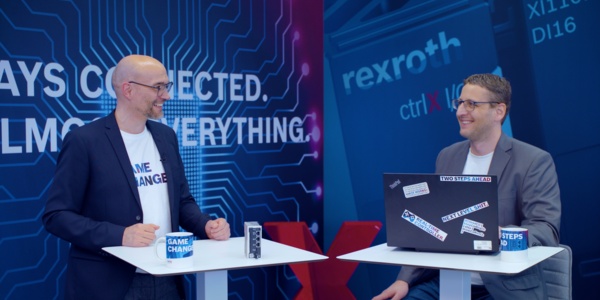 Gastgeber Christian Zentraf und sein Gast Kai Müller stehen an Besprechungstischen und sprechen über das Konfigurieren einer Handling-Applikation mit der ctrlX CORE, der Steuerungshardware der Automatisierungslösung ctrlX AUTOMATION