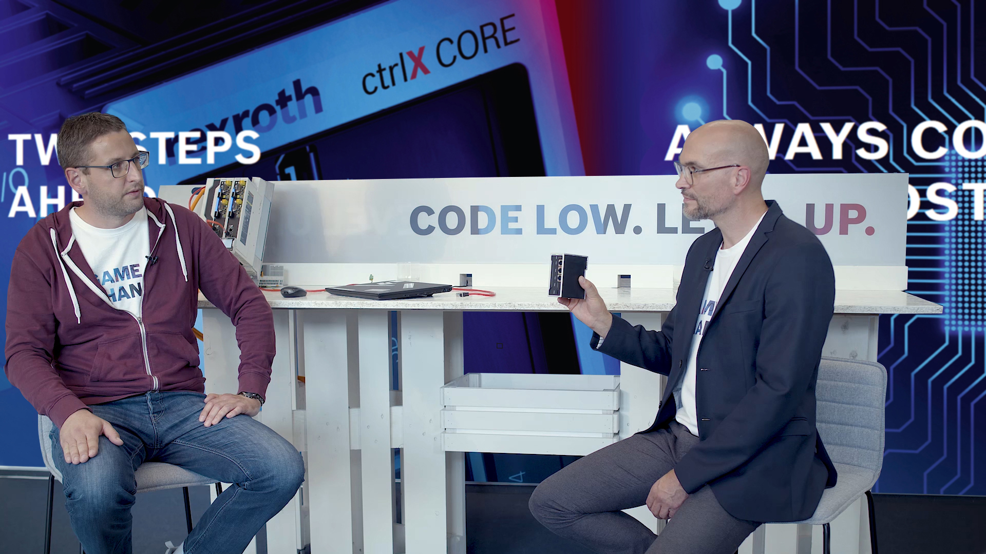 Gastgeber Christian Zentraf und sein Gast Kai Müller sitzen an einem Tisch und sprechen über die Inbetriebnahme der ctrlX CORE Steuerung