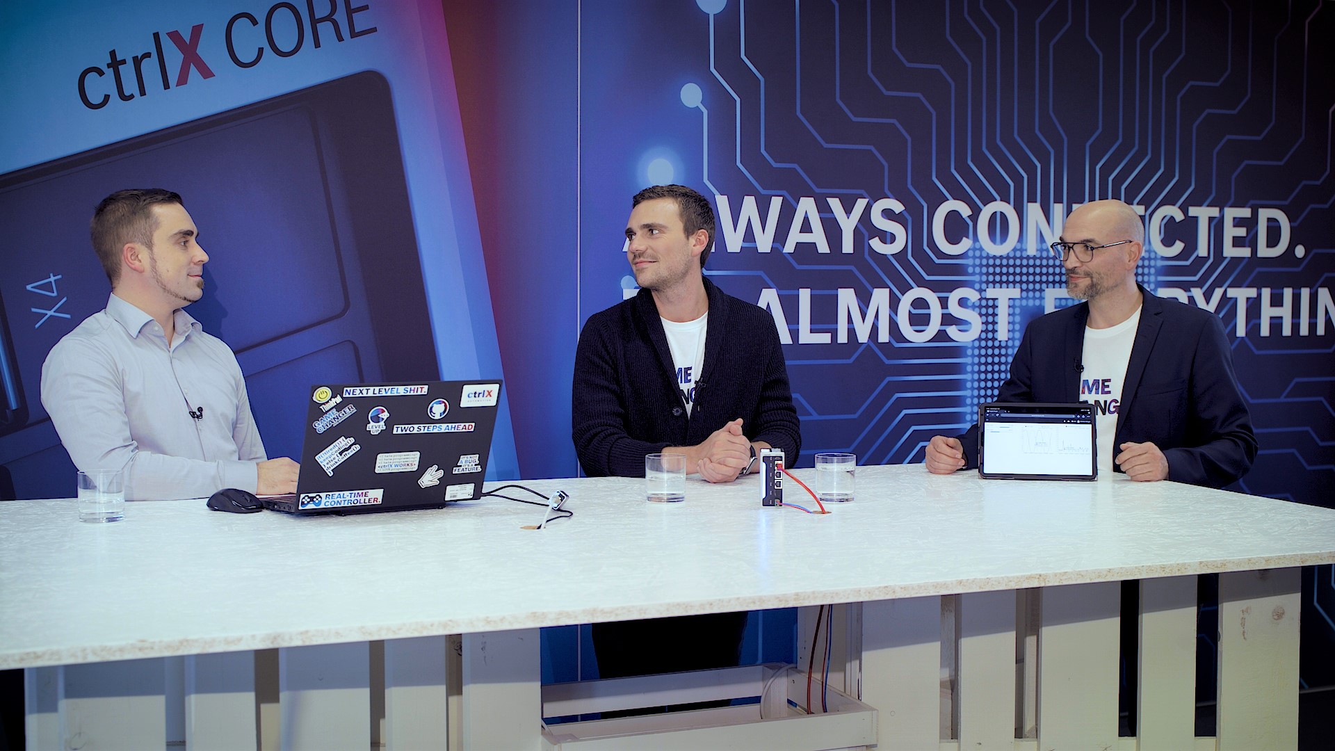 Gospodarz Christian Zentraf i jego goście Johannes Albrecht i Thomas Hepp (firma Mirasoft) siedzą przy stole i rozmawiają o rozwoju indywidualnych aplikacji partnerskich dla rozwiązania automatyzacji ctrlX AUTOMATION